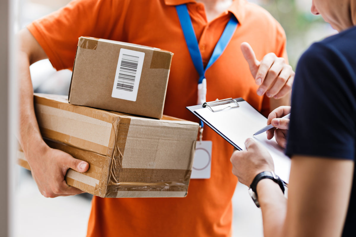 A recipient signing for a parcel handed over by a courier