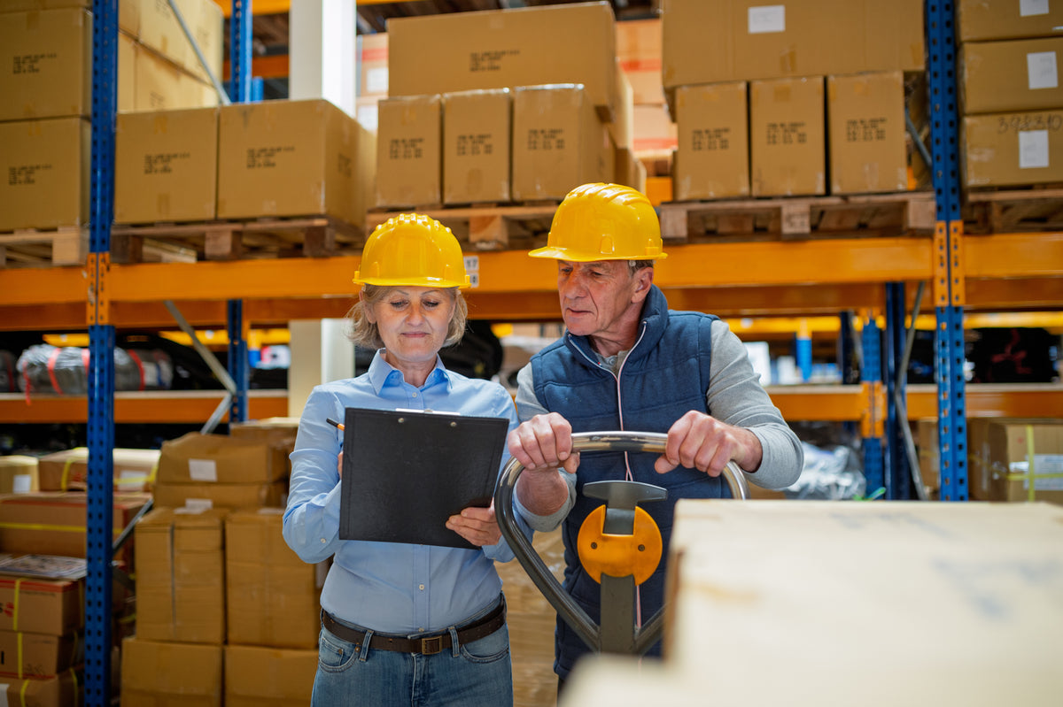 Two warehouse team members reviewing shipment paperwork