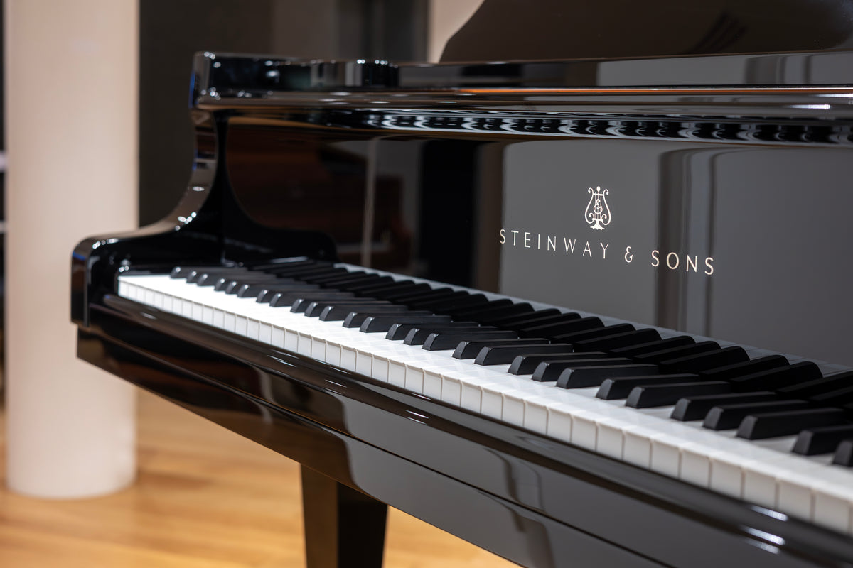 The polished cabinet and keyboard of a black Steinway grand piano