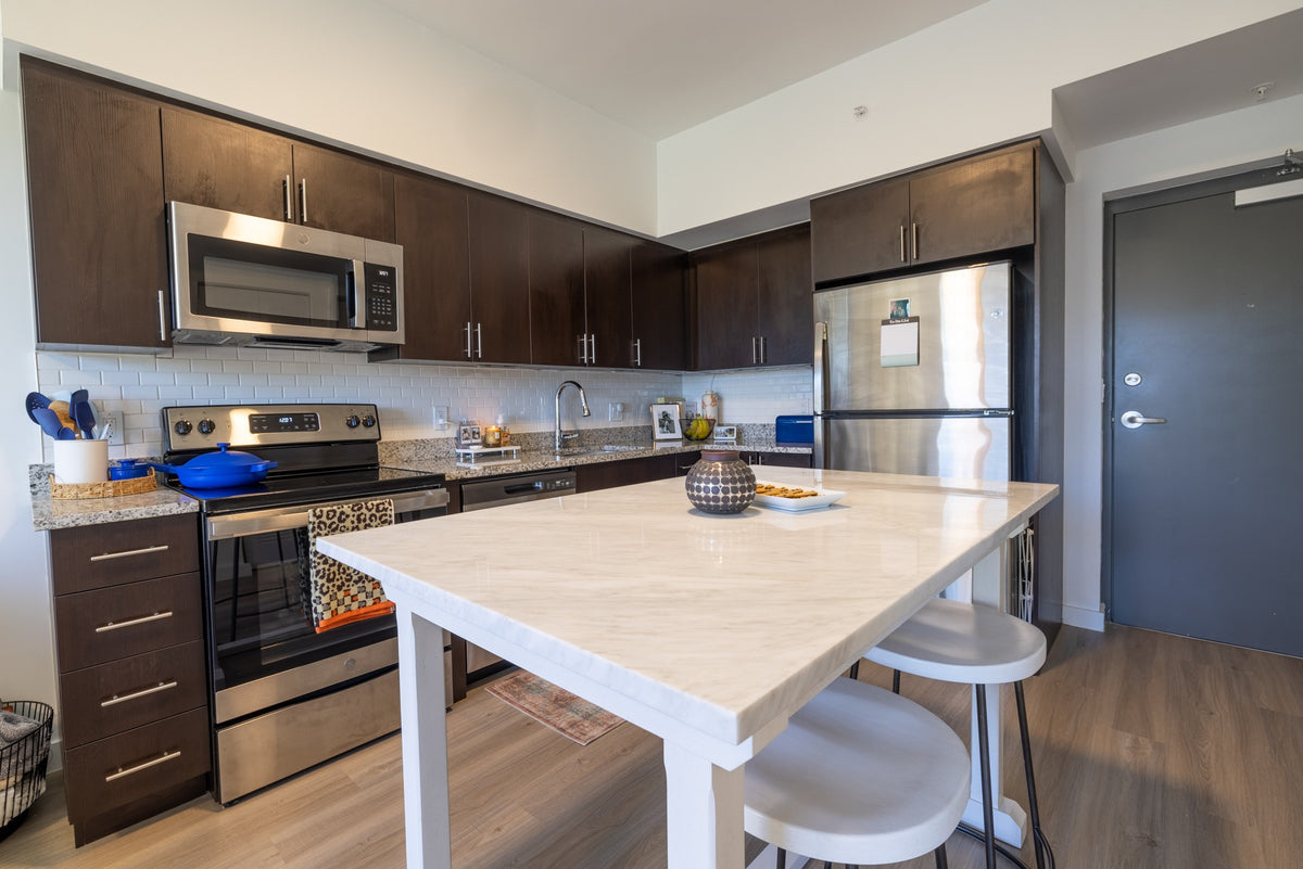 Apartment kitchen with dark cabinets, a white island and two white stools.