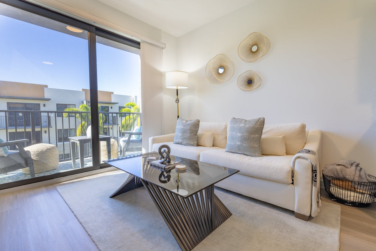 Cream sofa and sculptural glass coffee table arranged on a pale rug in the apartment living room.