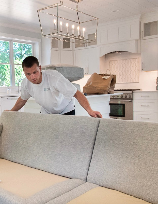 Movers wrapping an upholstered chair to protect it for the move